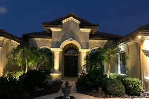 Front of a luxury home illuminated with frost-resistant landscape lighting in Northern Kentucky at night