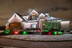 Snowy Kentucky home with colorful outdoor Christmas lighting on rooftop and landscape, showcasing warm white and multicolor holiday lights installed in winter.