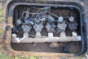 Sprinkler valve manifold with multiple irrigation control valves inside a valve box during sprinkler system inspection and repair