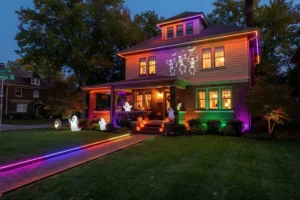 Cincinnati home decorated for Halloween with smart color-changing outdoor LED lights, glowing pathways, purple and green landscape lighting, pumpkins, and ghost decorations.