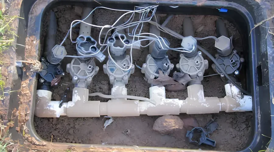 Sprinkler valve manifold with multiple irrigation control valves inside a valve box during sprinkler system inspection and repair