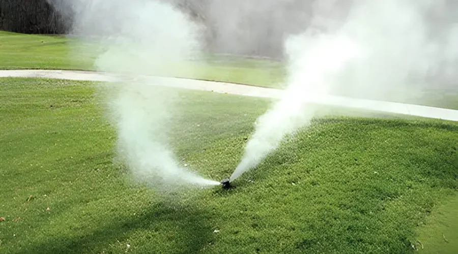 Sprinkler system releasing mist during winterization in Cincinnati, OH, showing how frozen irrigation pipes and valves can fail without proper maintenance.