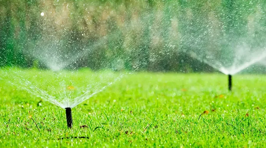 underground sprinkler system zones watering green lawn with multiple sprinkler heads spraying evenly across residential yard in Cincinnati