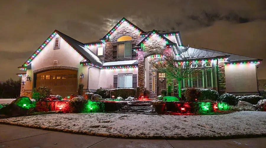 Snowy Kentucky home with colorful outdoor Christmas lighting on rooftop and landscape, showcasing warm white and multicolor holiday lights installed in winter.