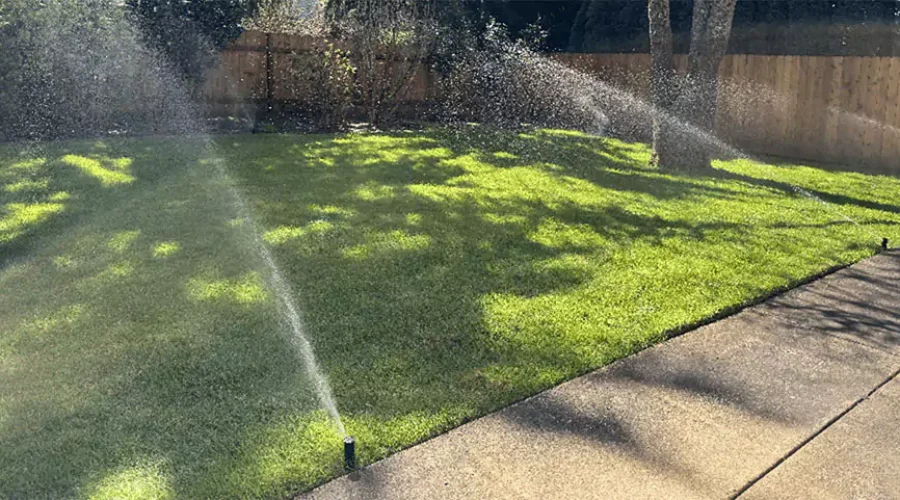 Automatic lawn sprinkler system watering a green backyard in Cincinnati, OH, keeping grass healthy and hydrated with even irrigation coverage.