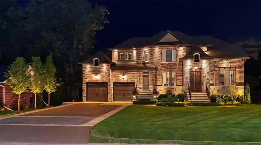 Luxury brick home with landscape lighting highlighting architecture, double garage, and manicured lawn at night in Cincinnati, OH.