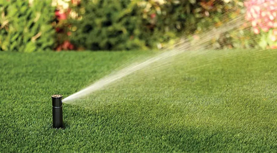 Pop-up sprinkler head watering a lush green lawn, providing efficient irrigation for healthy grass in Cincinnati, OH