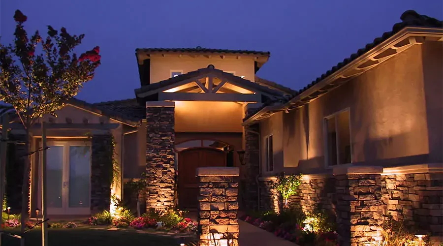 Elegant outdoor lighting highlighting stone pillars and garden areas of a modern home, creating a warm and inviting atmosphere.
